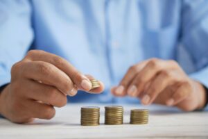 A hand reaching toward piles of coins signifying financial assets