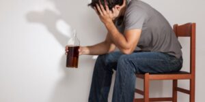 Person struggling with alcoholism sits with their head in their hands