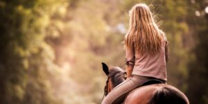 A girl with long hair riding a horse