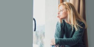 A lonely blonde woman stares out a window