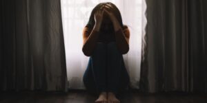 A woman sits with her head in her hands, depressed