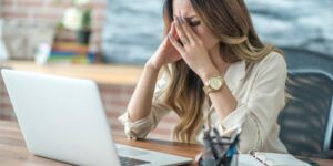 Woman sits at her computer looking stressed