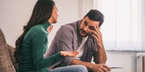 A man listening to his wife speak as he sits beside her at home