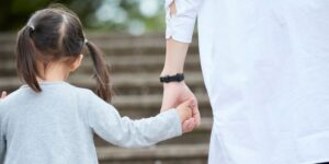 Young girl with pigtails holds hand of an adult