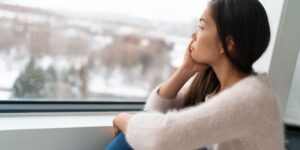 Woman looking sad while gazing out a window