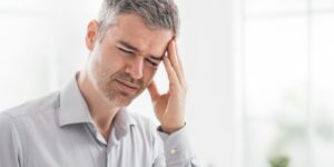 Stressed man with a headache massaging his temple