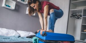 Woman packing suitcase in bedroom
